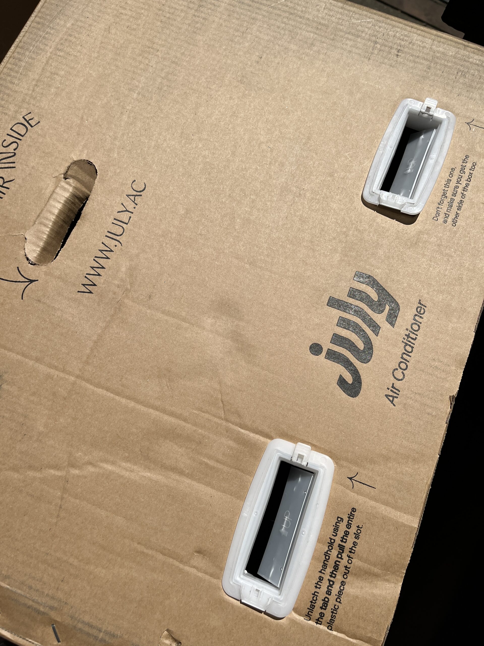Cardboard box with "July Air Conditioner" printed, including handles on the sides and the website URL www.JULY-AC.