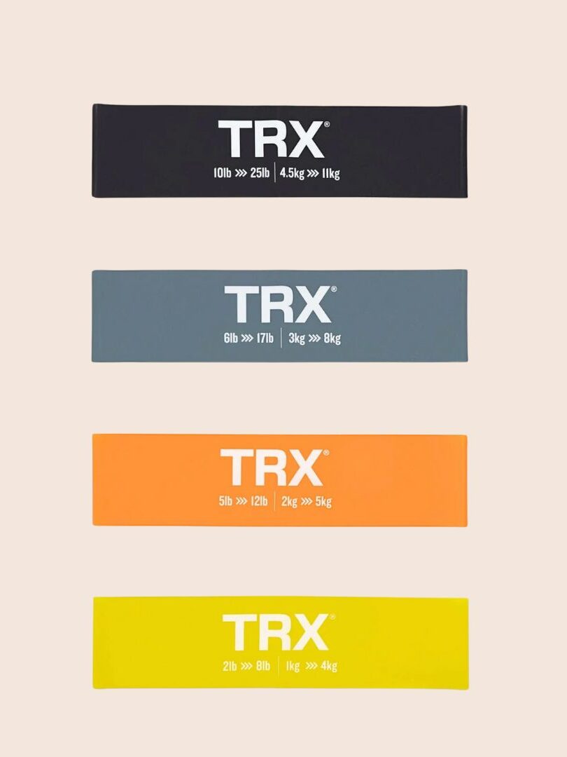 Four TRX resistance bands in black, gray, orange, and yellow are arranged vertically from top to bottom, each labeled with different weight ranges: 10-25lb, 6-17lb, 5-12lb, and 2-10lb respectively. Pair them with massage guns for an optimal workout recovery routine.