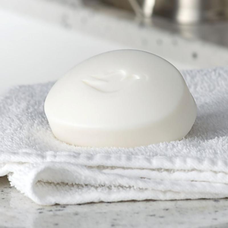 A white bar of soap with a bird logo embossed on top is placed on a white folded towel on a bathroom countertop.