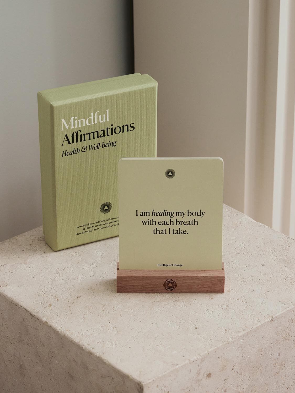 A box labeled "Mindful Affirmations" sits beside a wooden stand, holding a card that reads, "I am healing my body with each breath that I take".