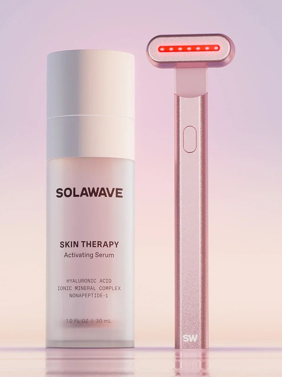 A bottle of Solawave Skin Therapy Activating Serum sits beside a pink skincare tool with a red light.