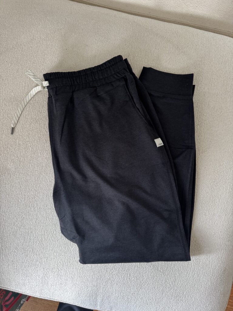 Black joggers with an elastic waistband and drawstring, folded neatly on a light-colored surface.