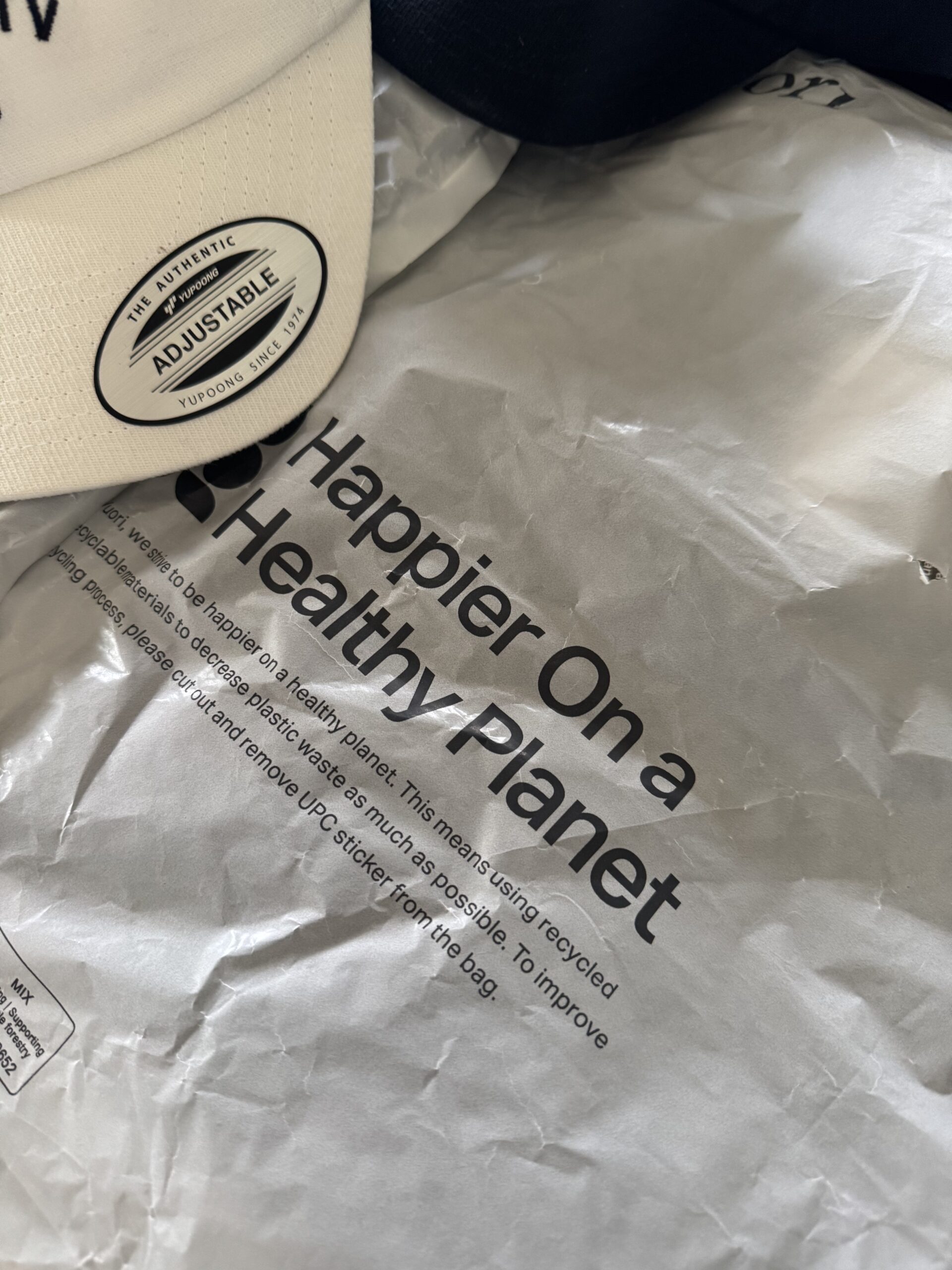 Close-up of a package with text: "Happier On a Healthy Planet," next to the adjustable label on a cap.