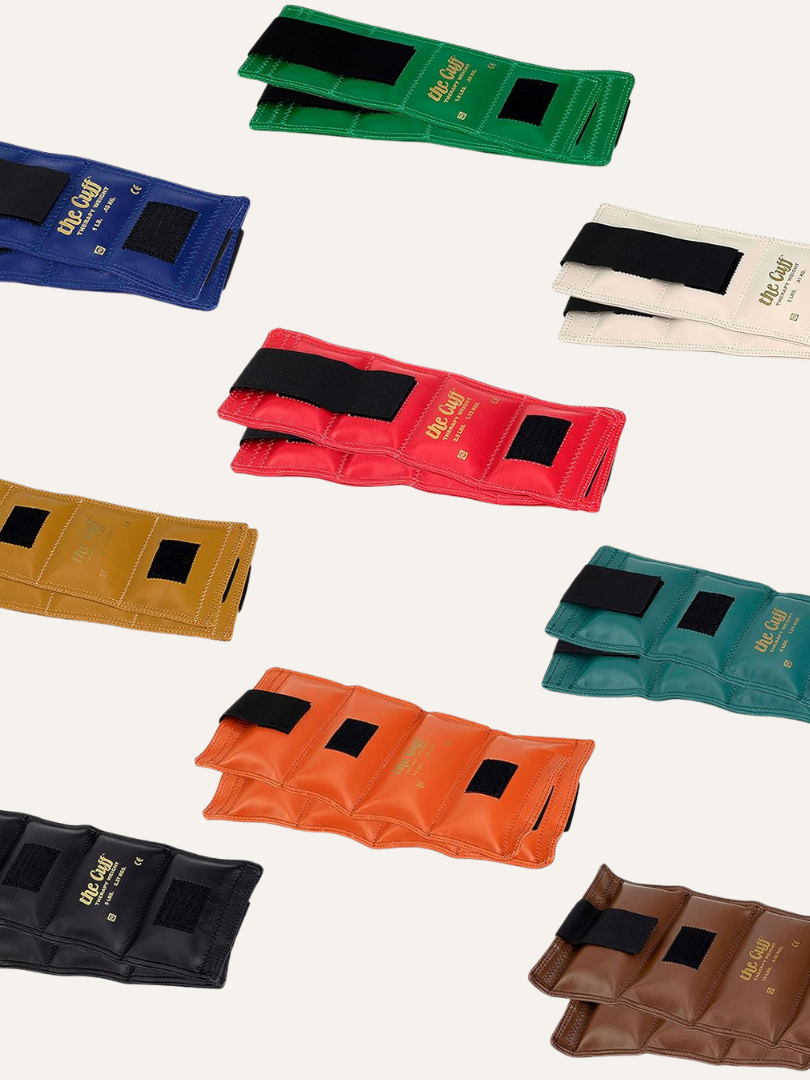 Various colored ankle weights with Velcro straps sit alongside sleek massage guns, all arranged on a light background.